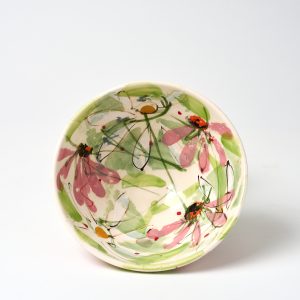 A photo of a ceramic bowl, propped up on its edge so the hand painted floral design of the interior can be seen.