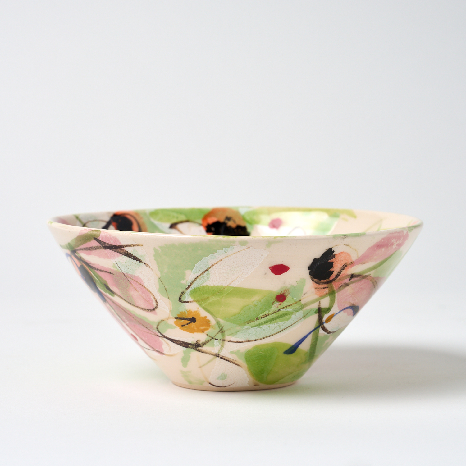 A photo of a hand thrown and decorated ceramic bowl. This small bowl features a hand painted floral design.