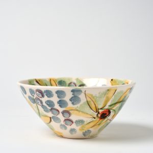 A photo of a ceramic bowl with a hand painted blue spots with yellow daisies design.