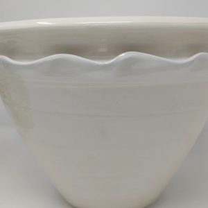 A photo of a hand thrown, white earthenware glazed cache pot.